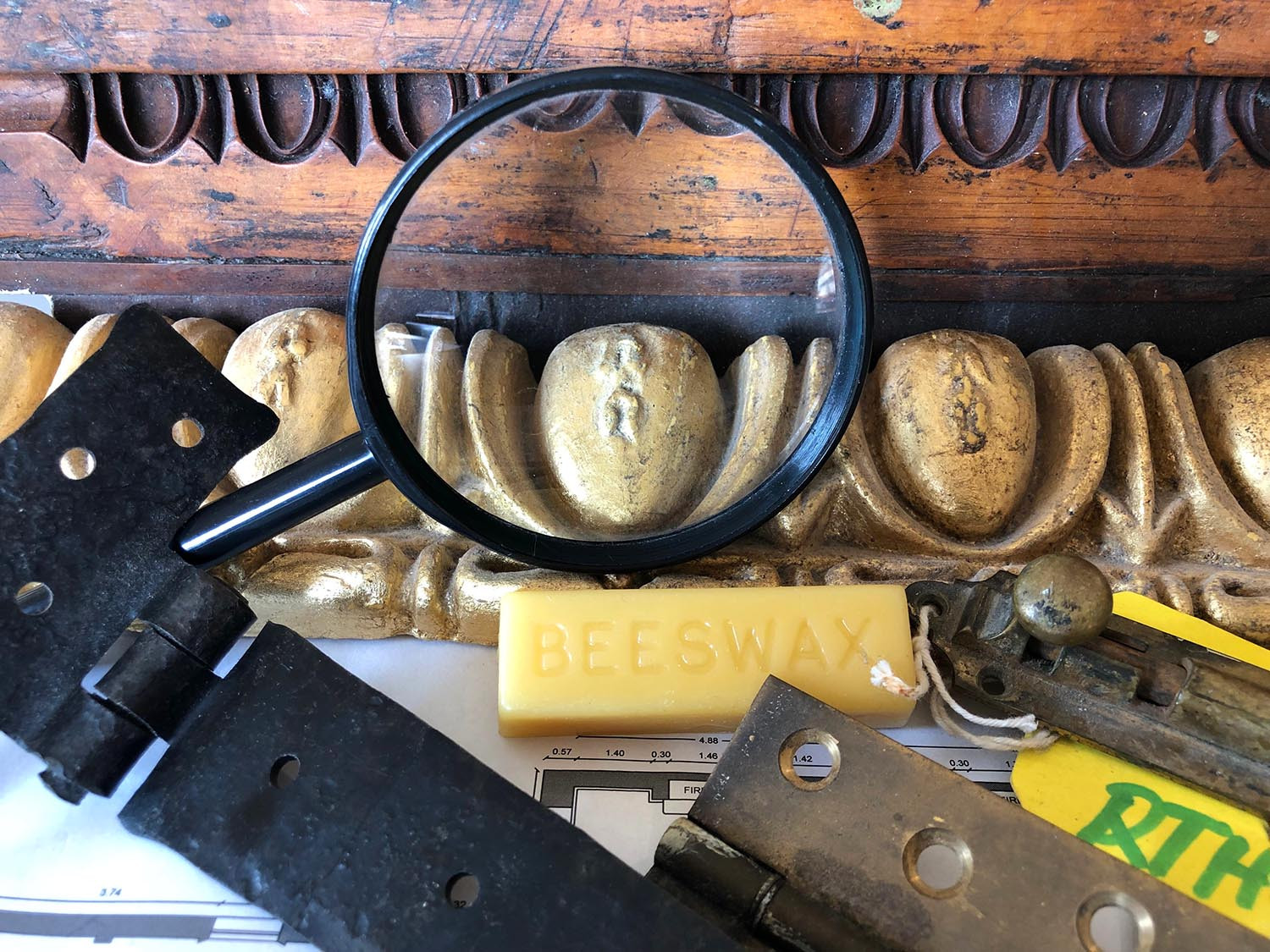 Photo showing a variety of objects, including wooden mouldings, a metal hinges, building plans and other ephemera