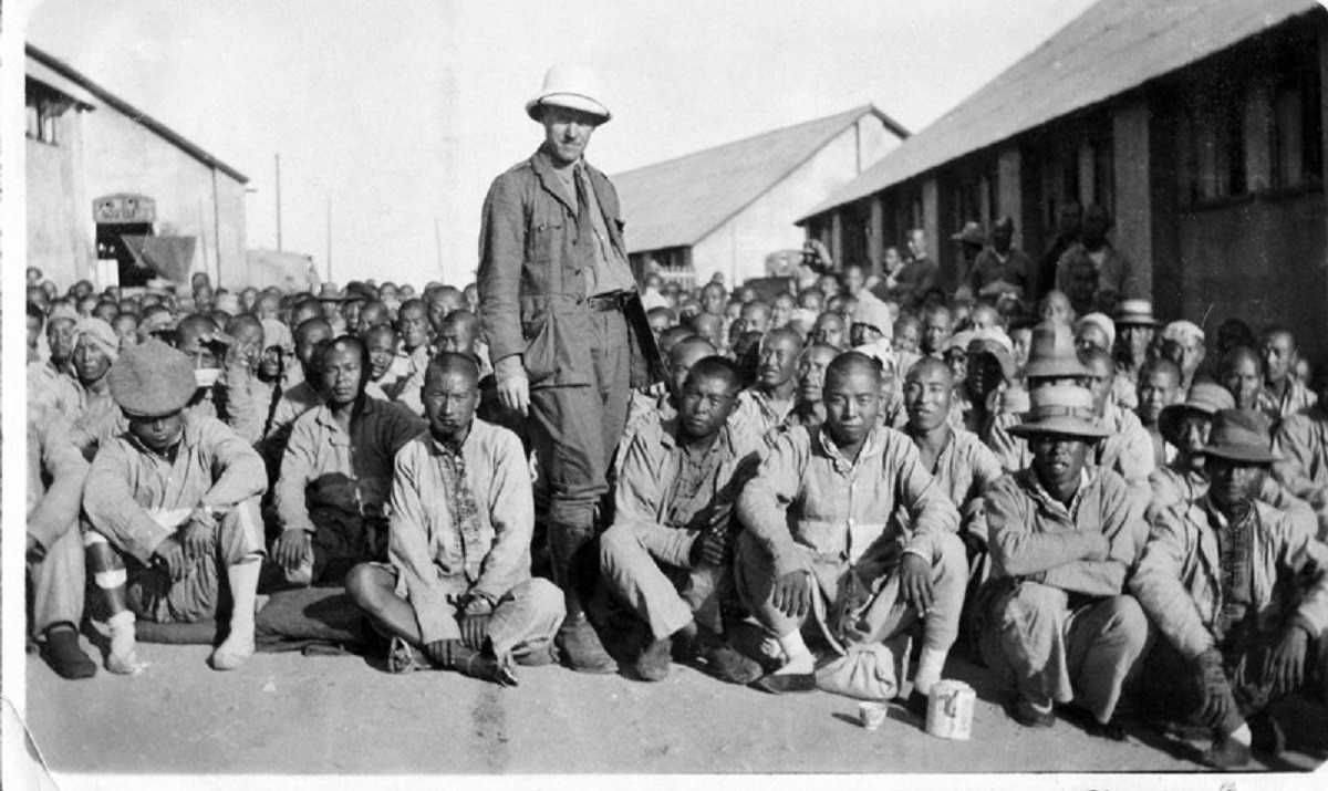 Black and white photograph showing Chineses workers seated on the ground  